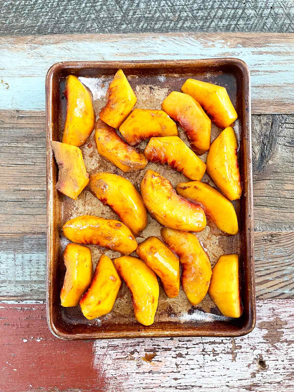 Baking sheet with peaches, sprinkled with cinnamon, sugar, and nutmeg.
