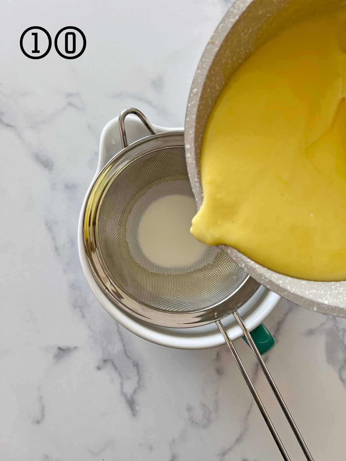A bowl is being filled with a ice cream base through a strainer.