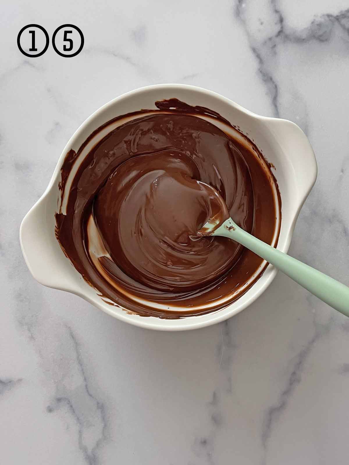 Melted chocolate in a white bowl with a spoon.