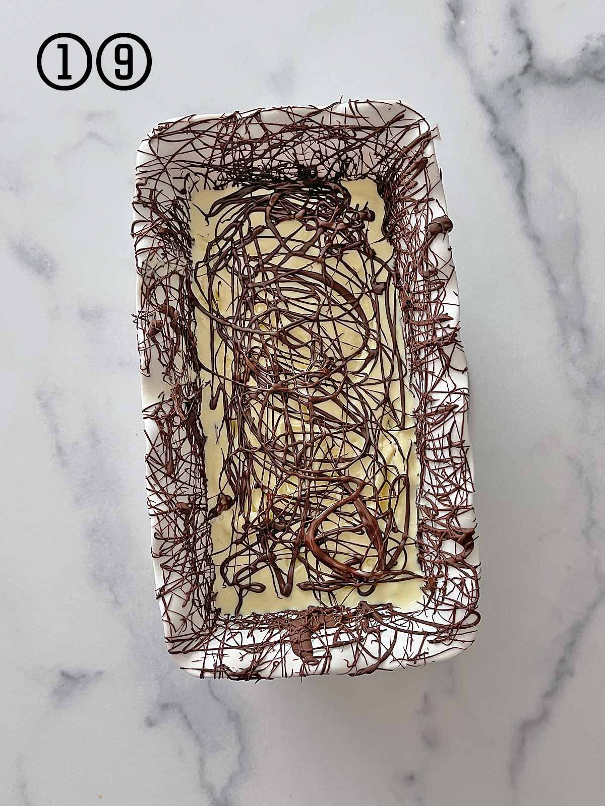 Mint chocolate chip ice cream in a loaf pan on a marble table.