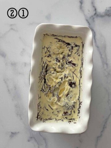 A bowl of mint chocolate chip ice cream on a marble table.