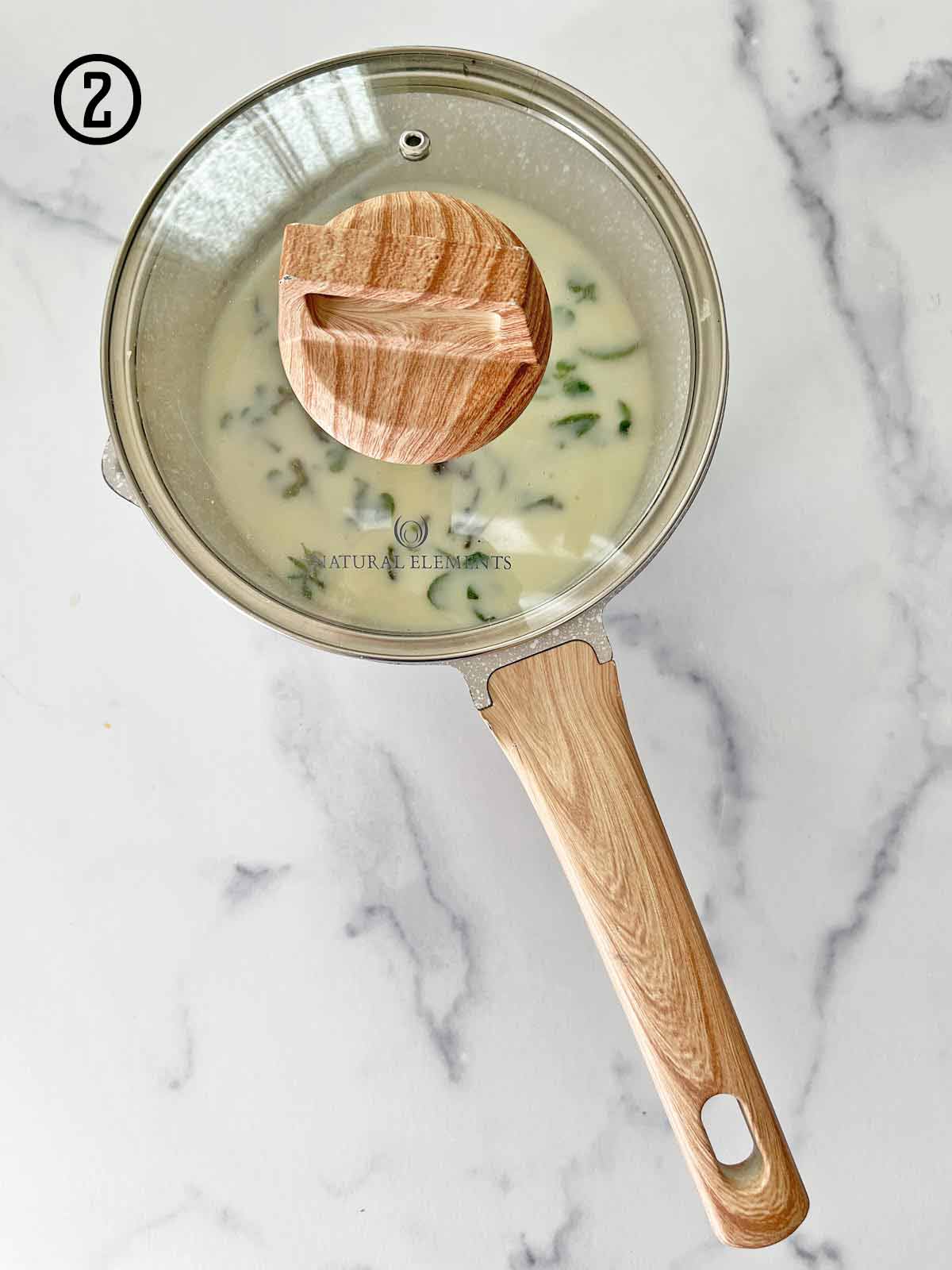 A pan with mint steeping in a covered pot of milk and cream.