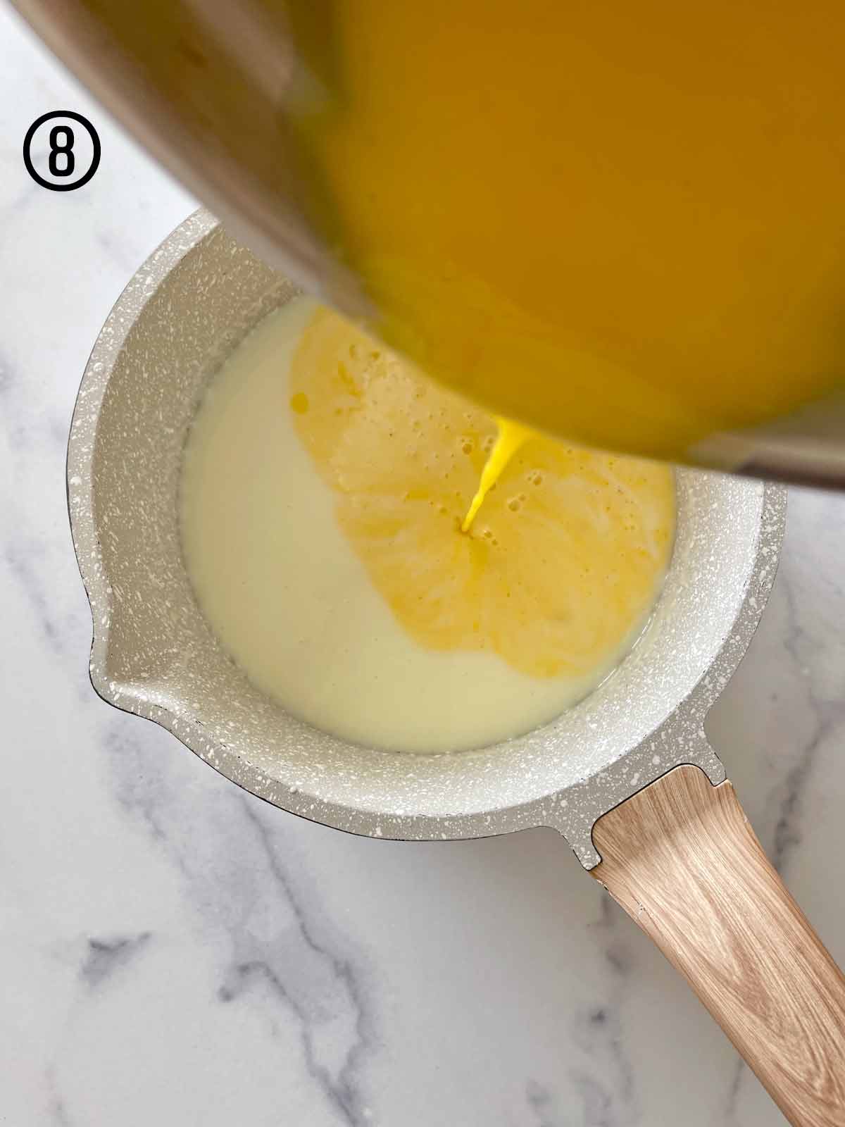 Mint chocolate chip ice cream base is being poured into a saucepan.