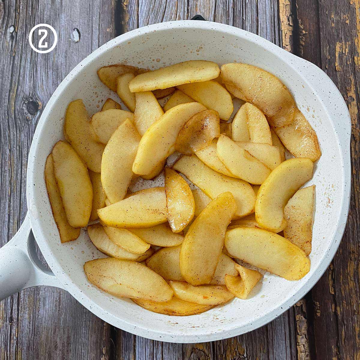 Easy apple pastry recipe with sliced apples in a pan on a wooden table.