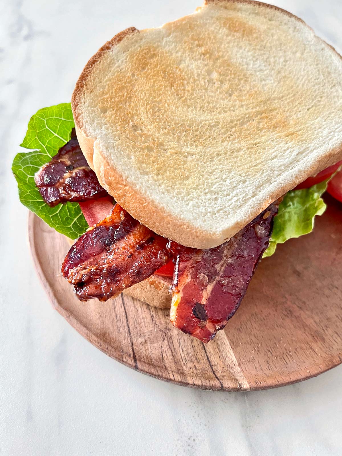 Candied bacon, lettuce, and tomato sandwich with white bread lightly toasted