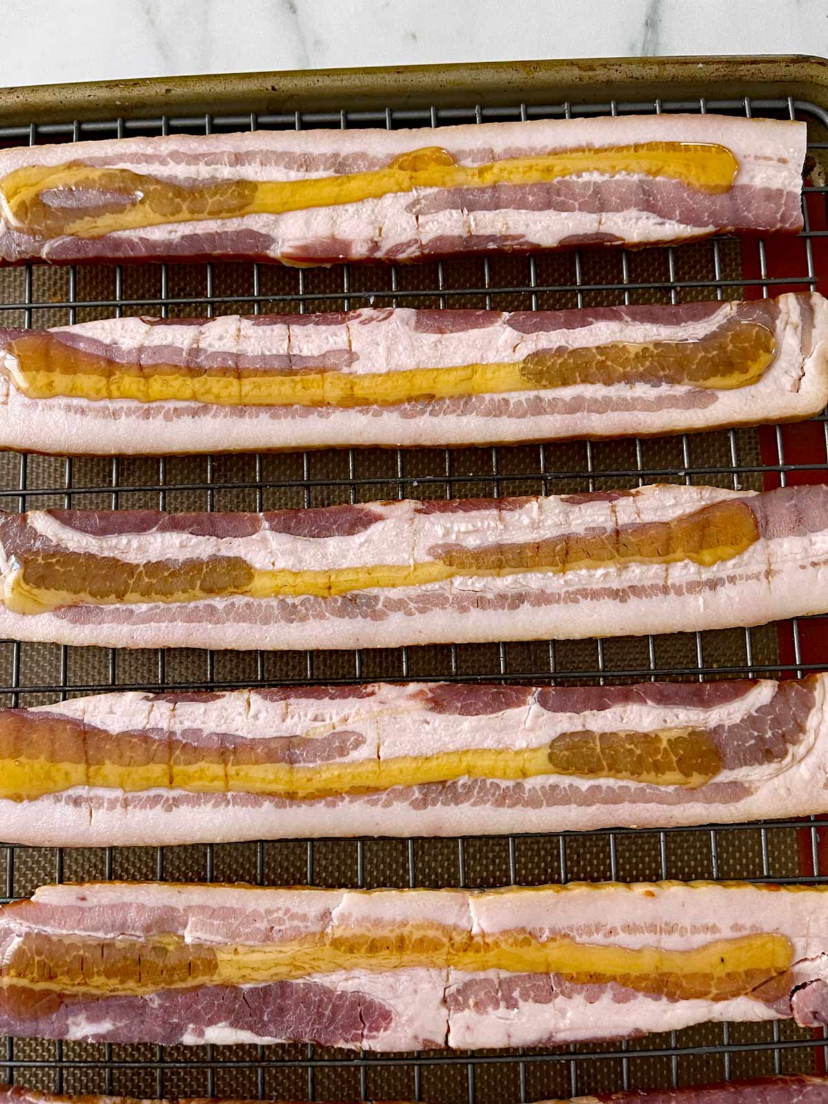 Slices of bacon with a strip of honey poured down the middle.