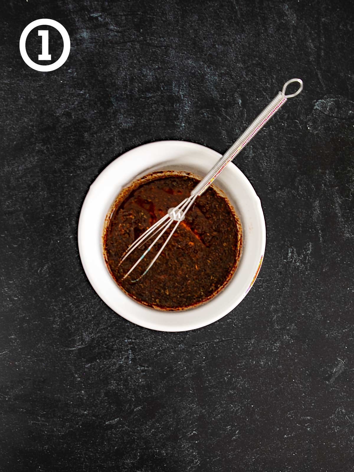 A bowl of Grilled Chicken Fajitas marinade with a whisk.