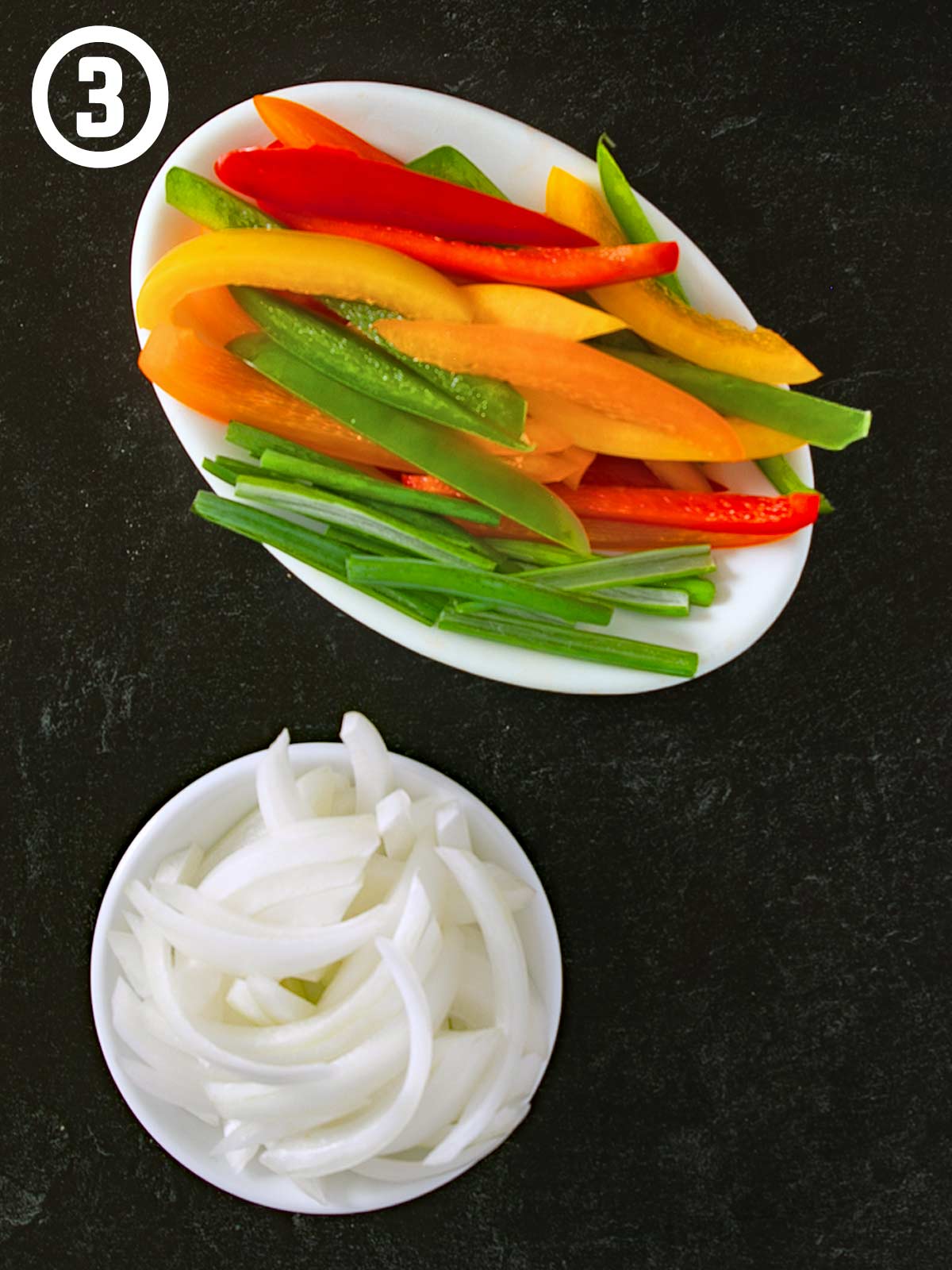 Grilled chicken fajitas peppers and onions on a black surface.