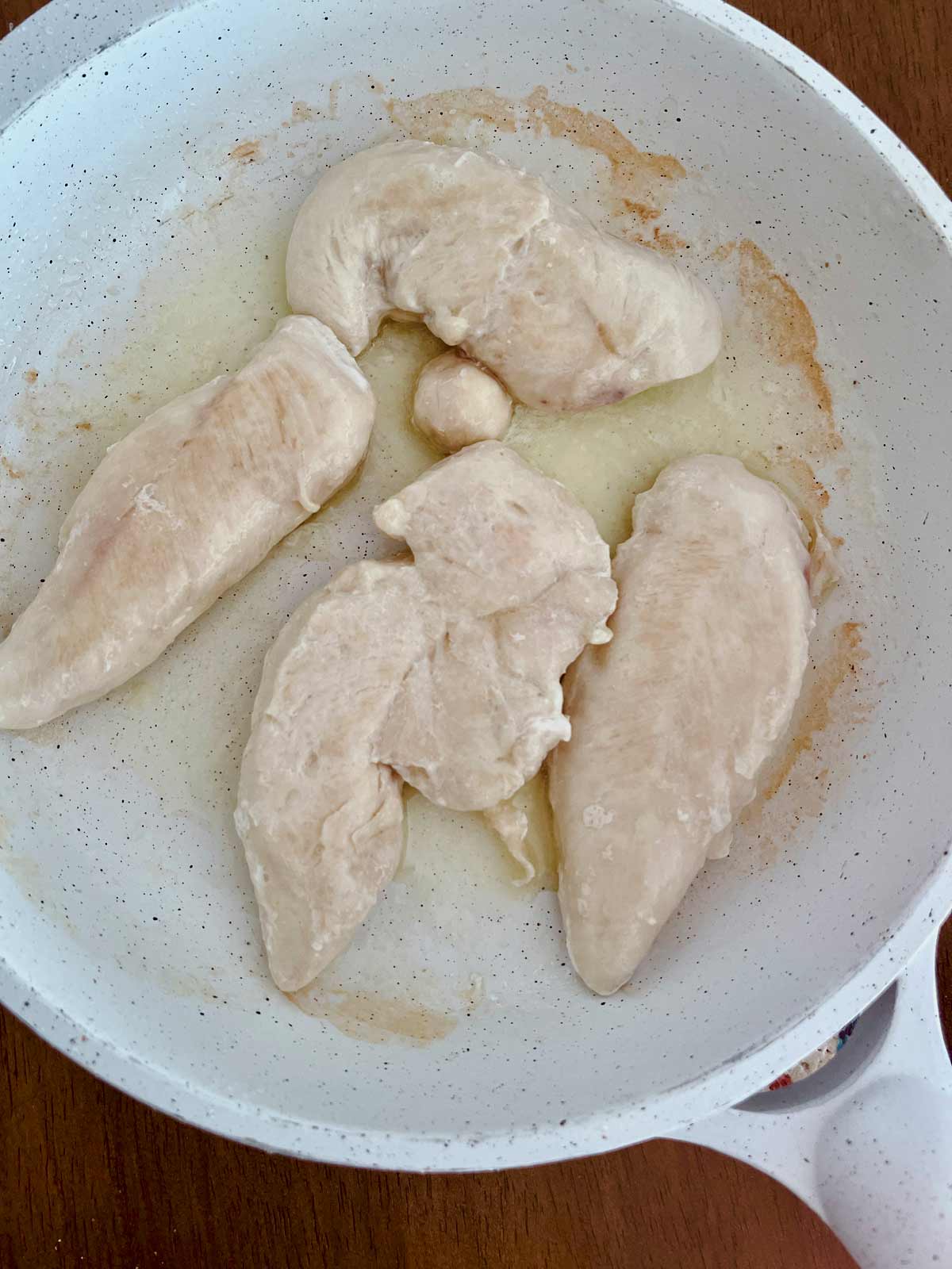 Skillet with chicken tenders cooking.