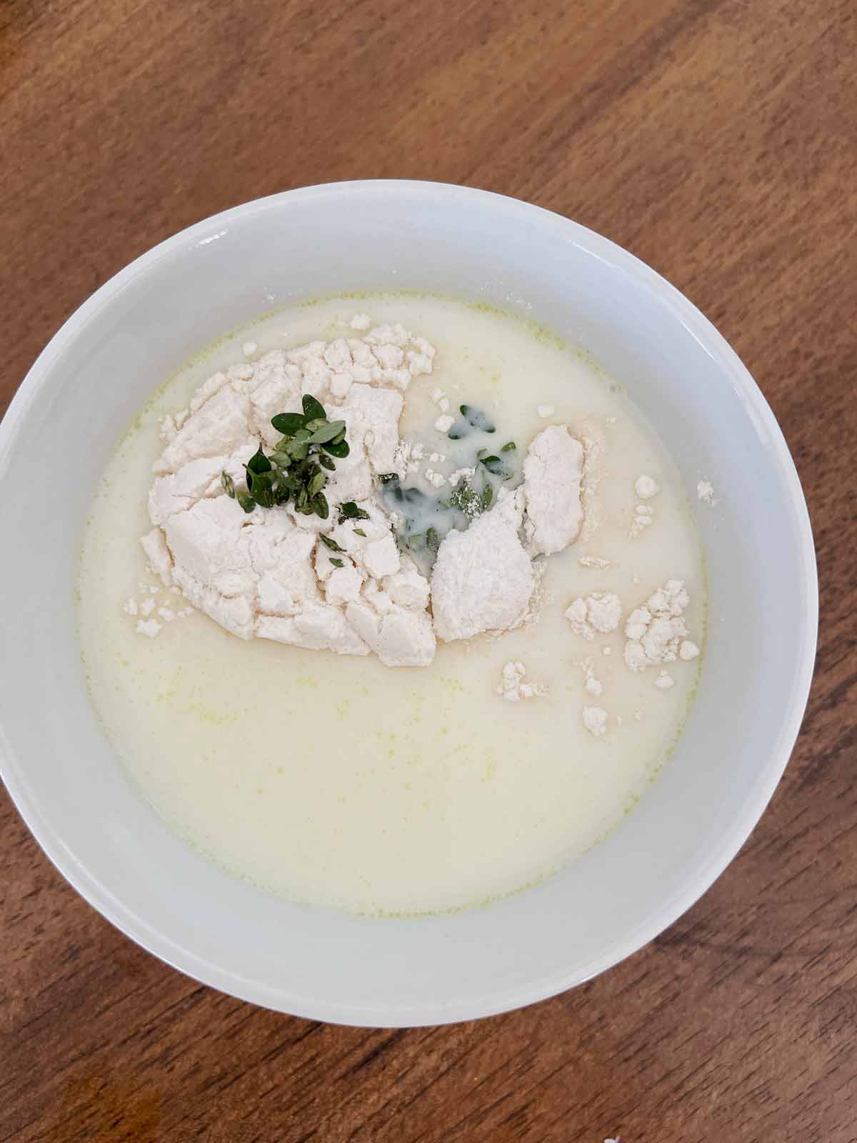 Bowl with milk, flour, thyme, broth garlic, and salt.