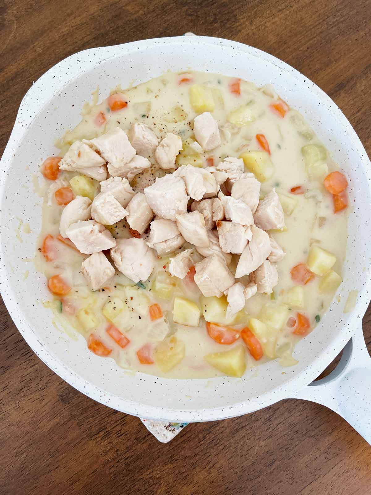 Chicken has been added to the vegetables in the skillet.