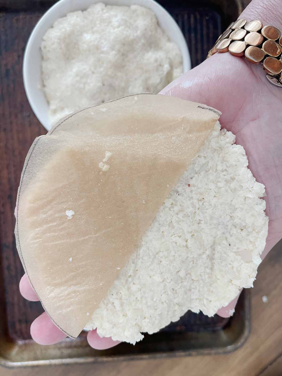 Dough with parchment filpped over and parchment being pulled off.
