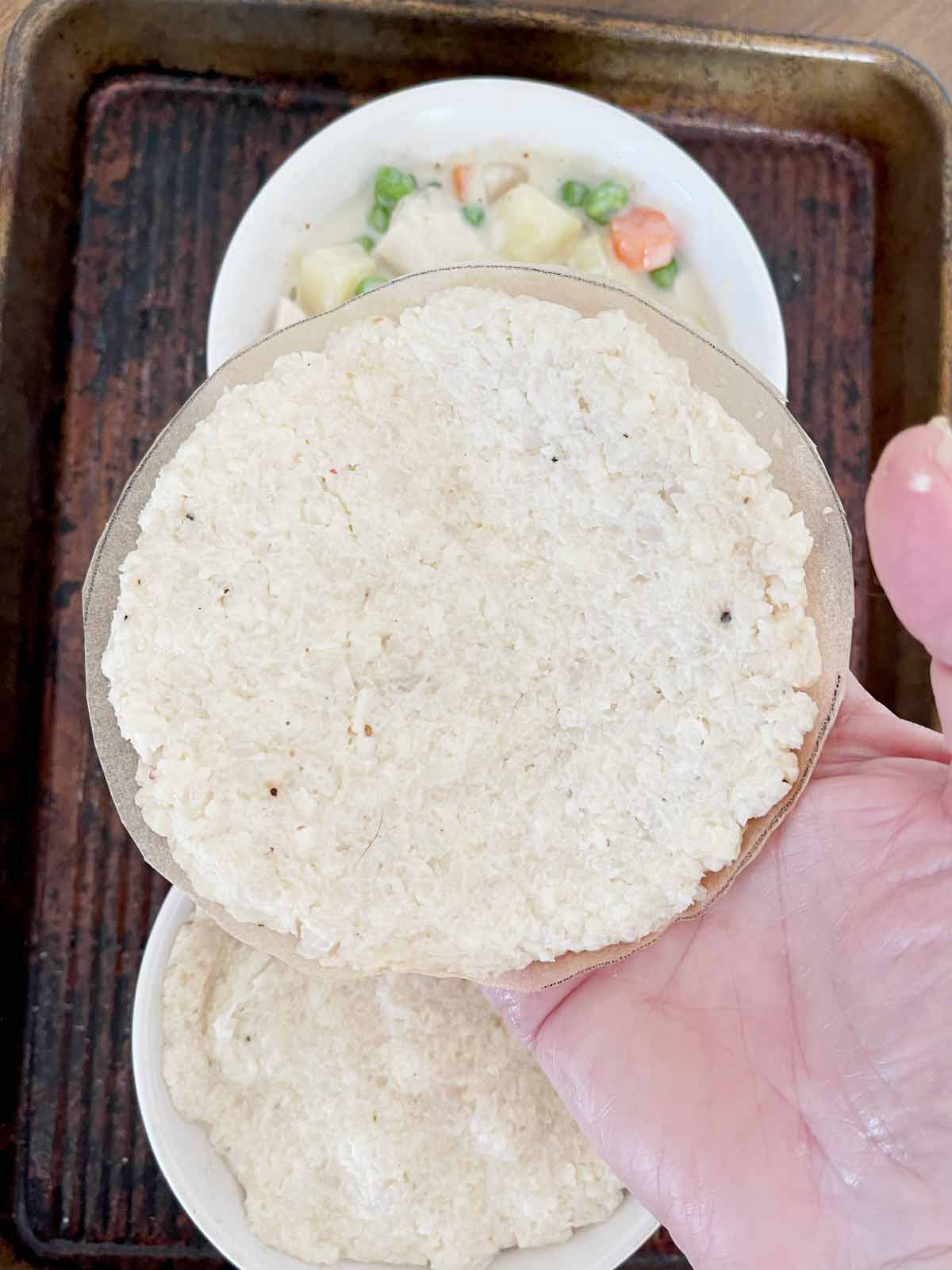 Parchment with dough on palm of hand.