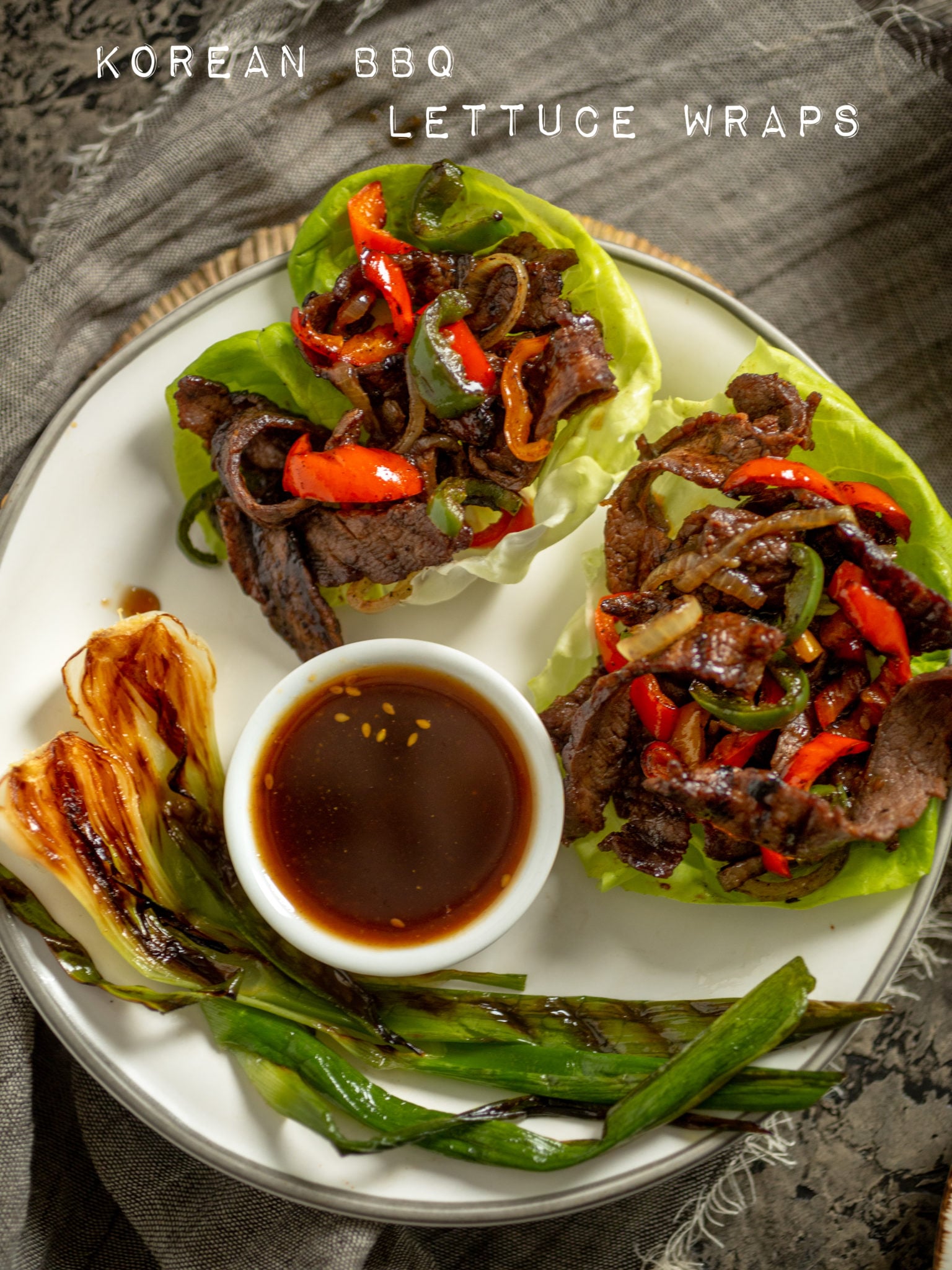 Picture of a plate of korean BBq inside a lettuce cup with grilled scallions.
