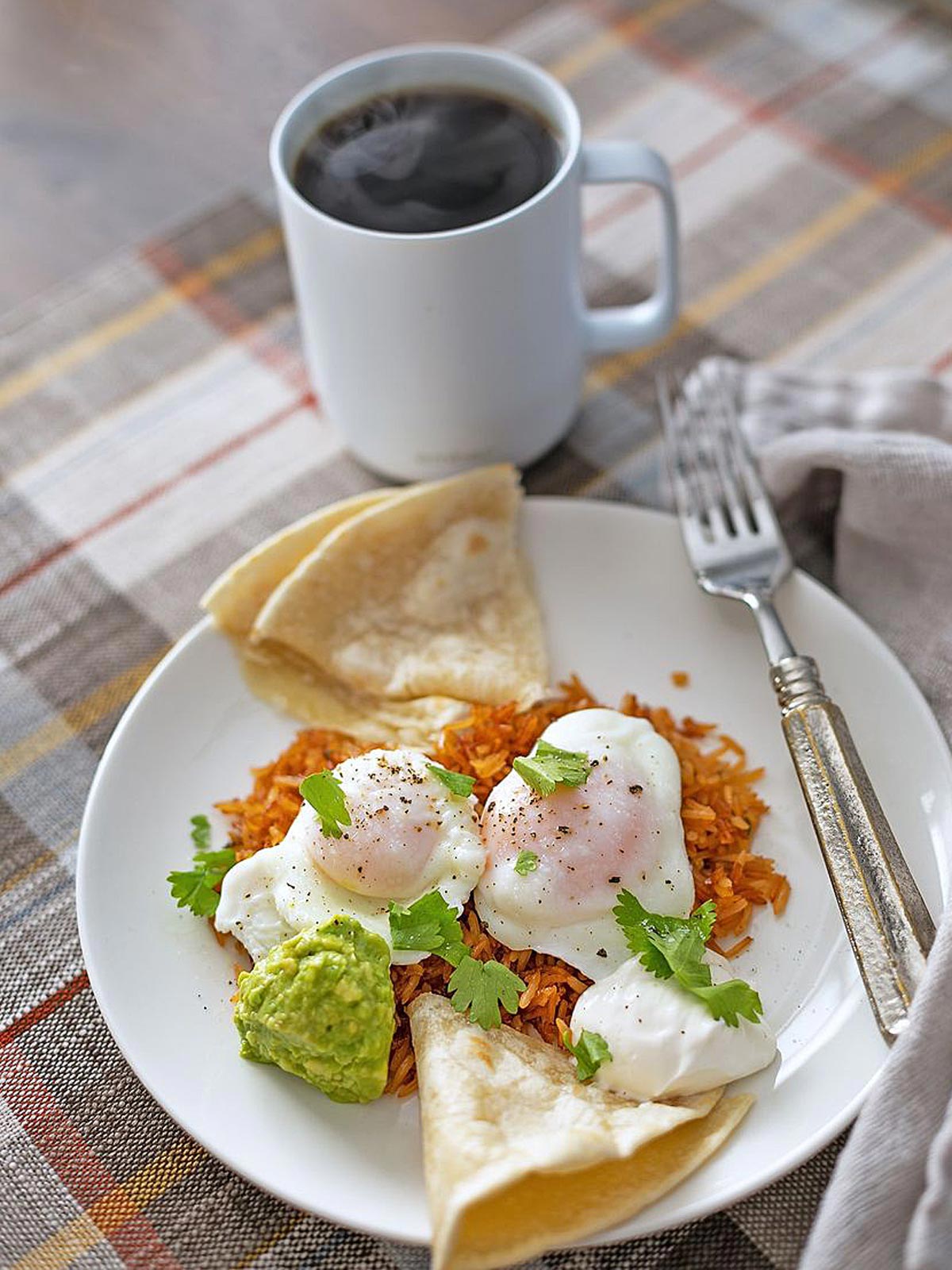Cup of coffee with plate of Mexican Rice and poached eggs.