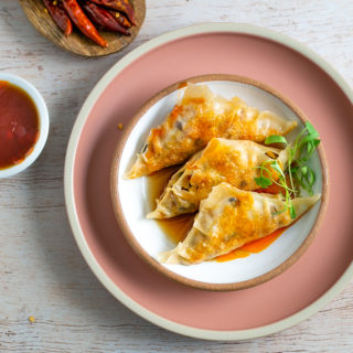 Plate of potstickers with sauce.