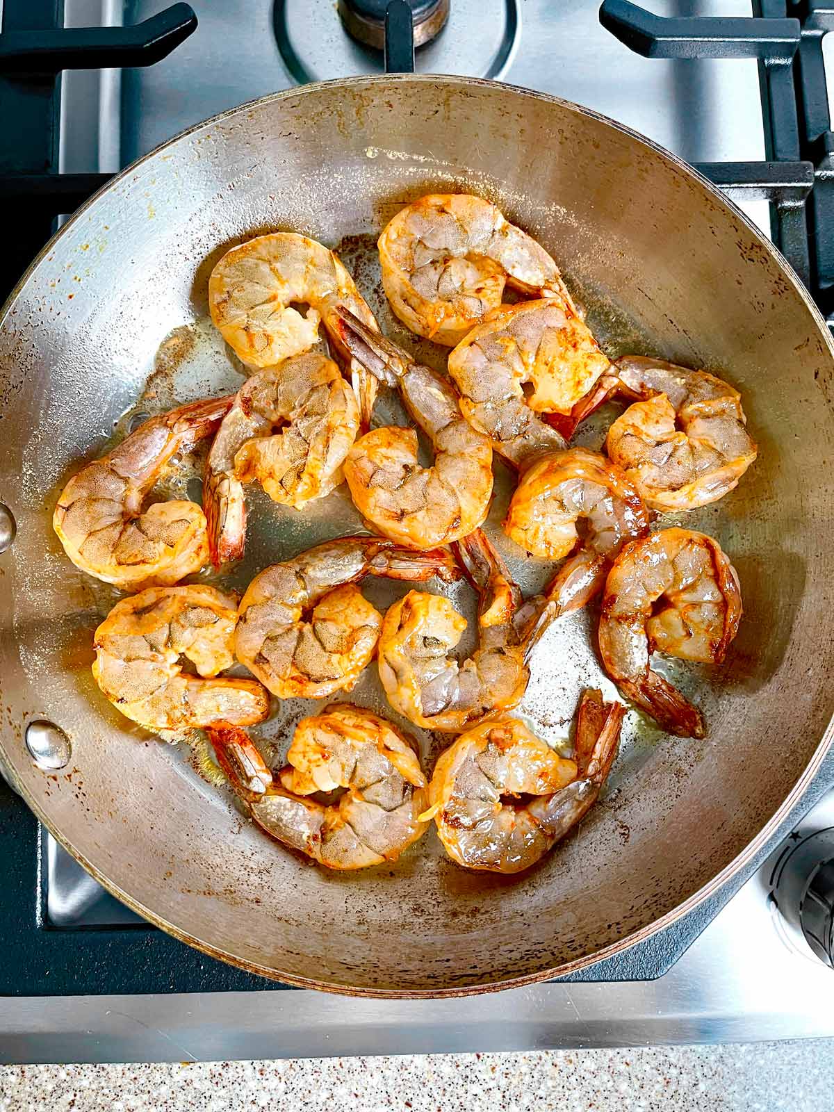 Shrimp in saute browning on one side.