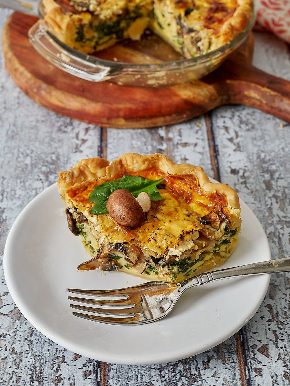 Slice of quiche on plate with fork and one bite missing.