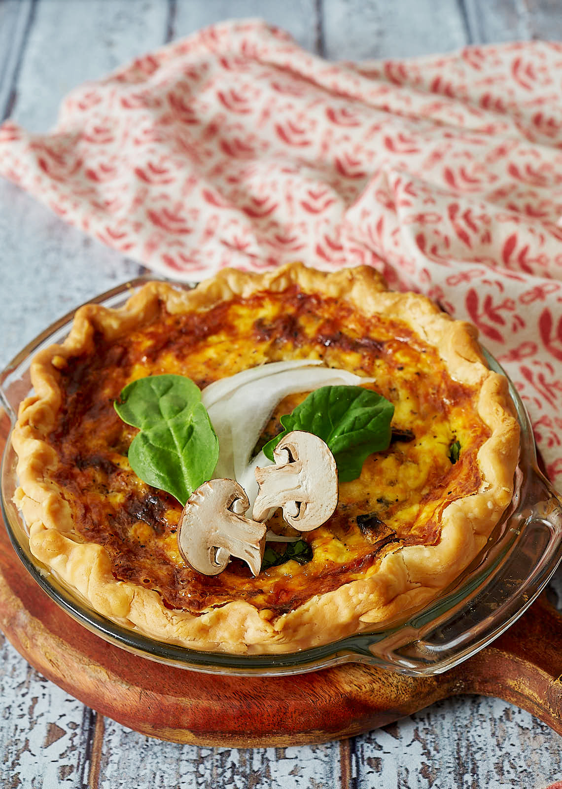 Quiche with mushrooms and spinach garnish.