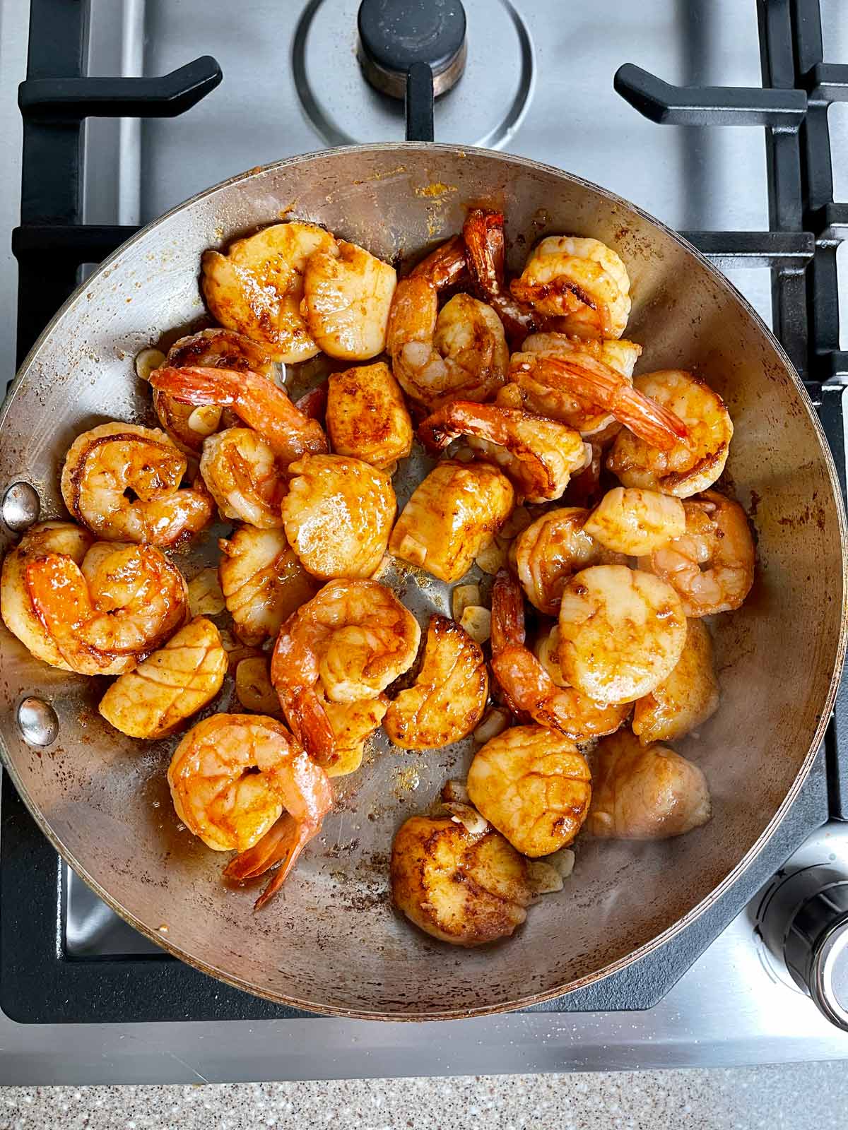 Fully browned shrimp and scallops in frying pan