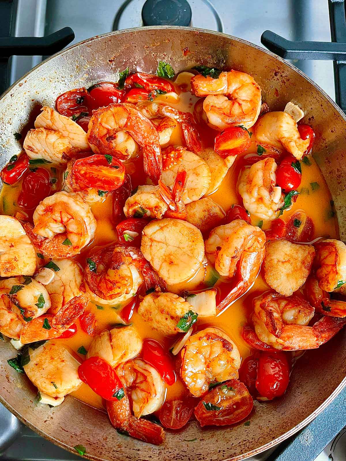 Seafood added back to tomatoes and broth 
In pan