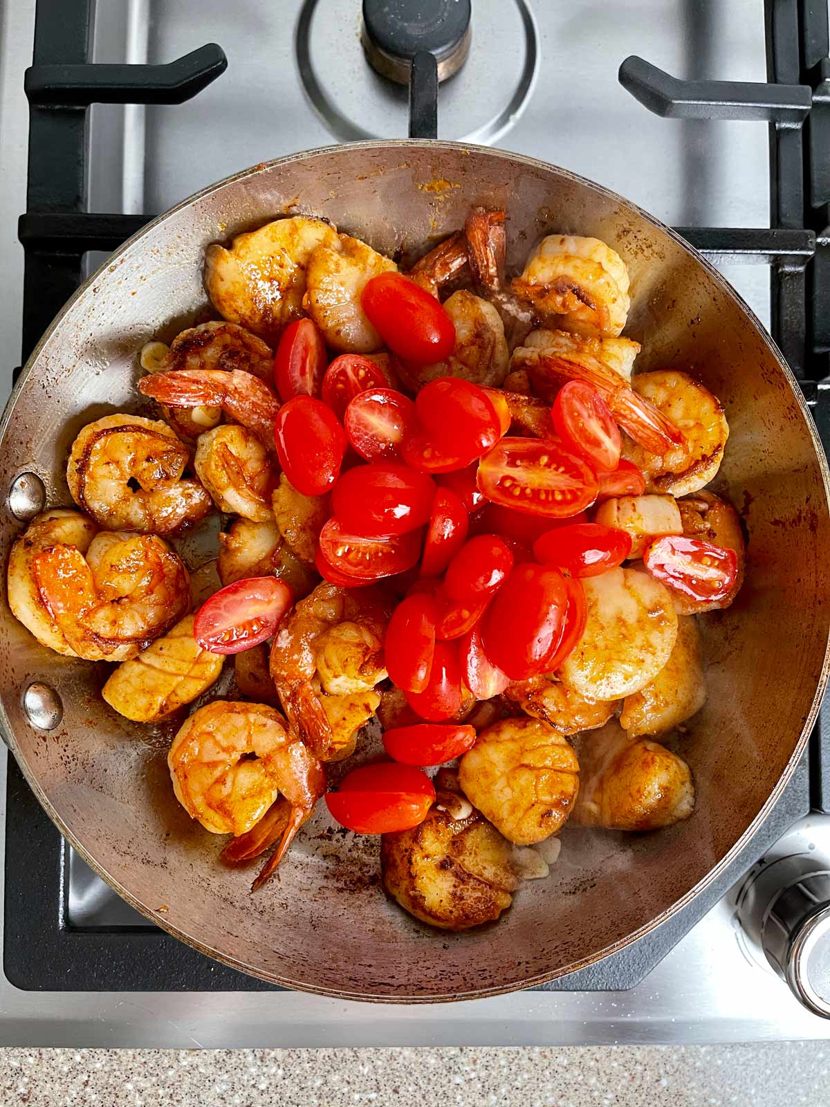 Halved cherry tomatoes added to pan with shrimp and scallops