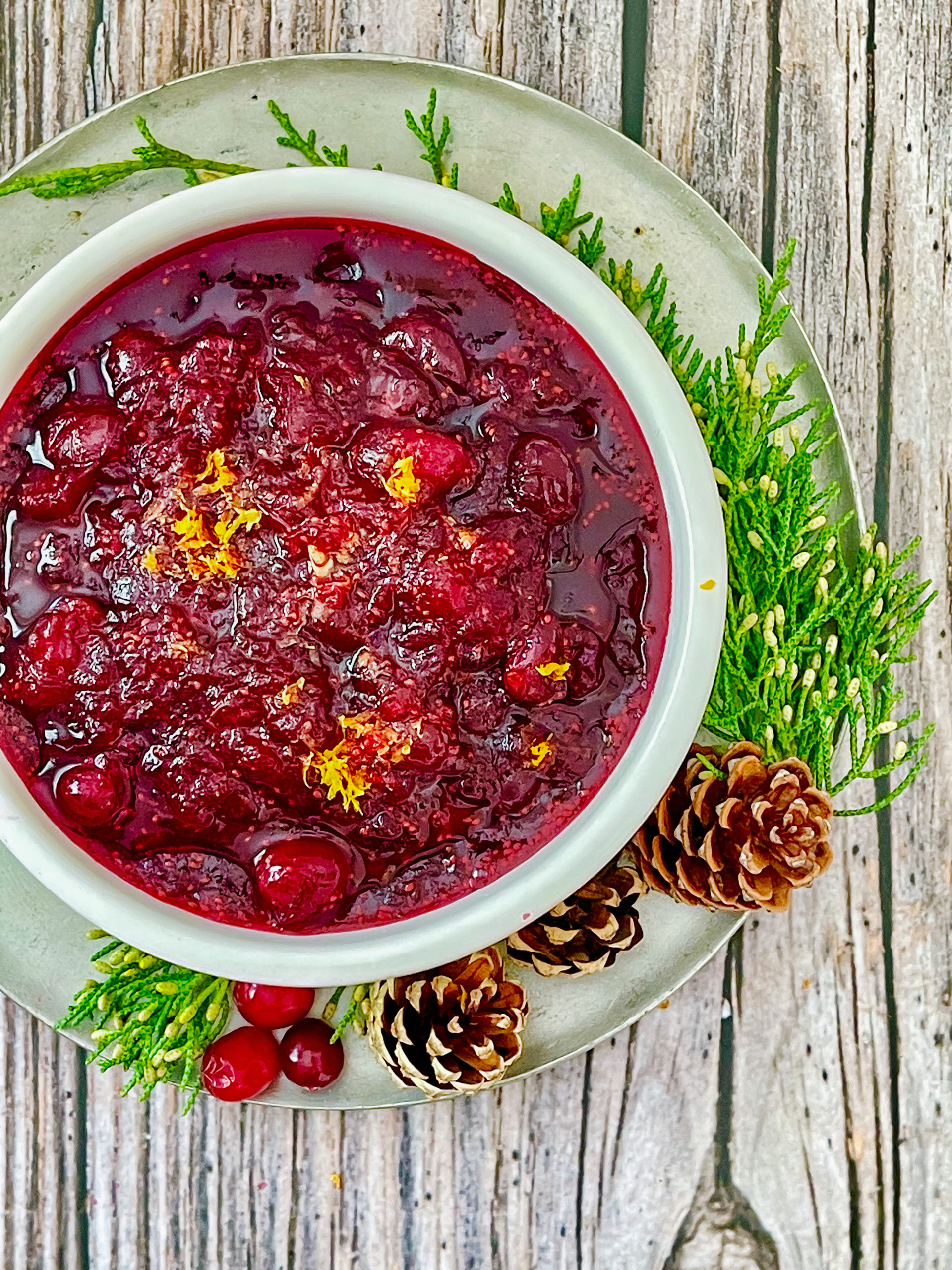 Bowl of cranberry sauce and hilly bough and pinecones