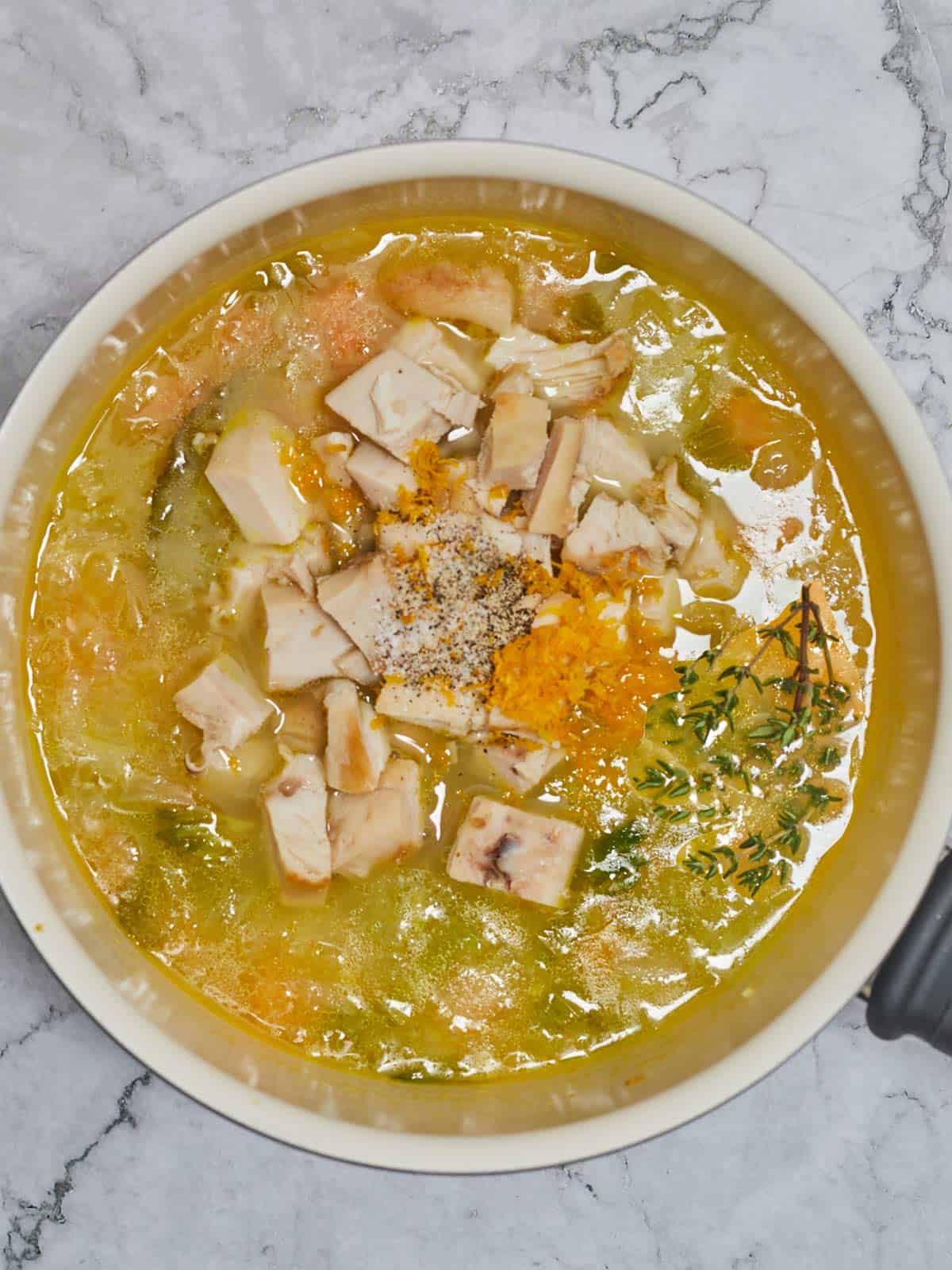Salt, pepper, and lemon zest added to the skillet with the soup.