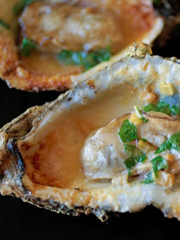 Grilled oyster with butter and parsley in oyster shell.