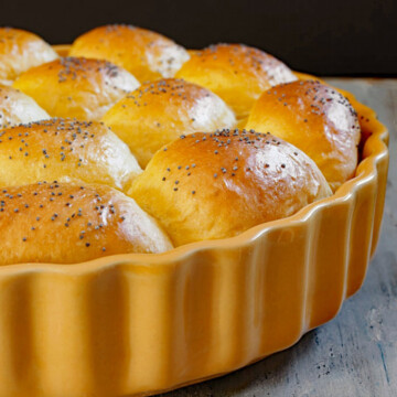Pan with raised and baked sinner rolls with poppy seeds on top.

