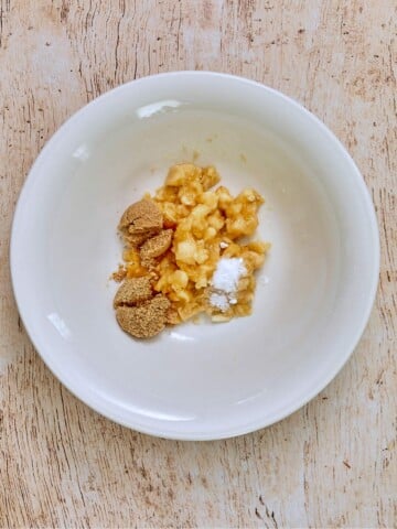 Mashed bananas in a bowl with brown sugar salt and baking soda.