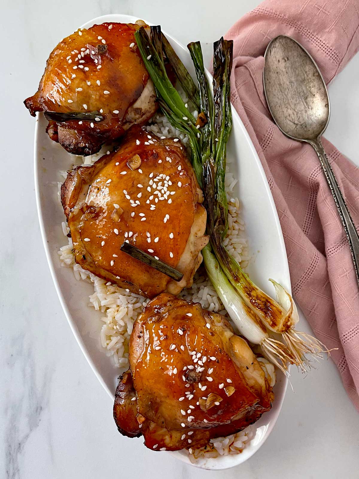 Aloha Shoyu Chicken Recipe served on a white oval platter with rice, pan drippings and grilled green onions.