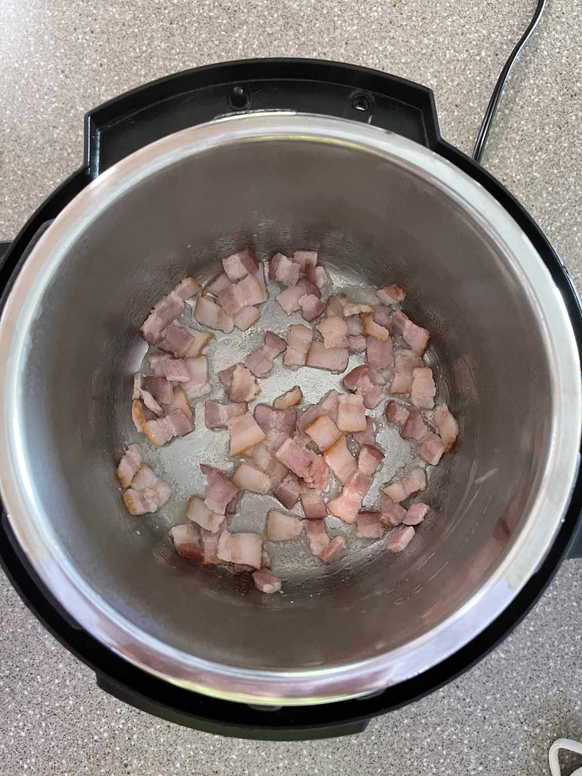 Bacon cooking in the bottom of pressure cooker pot.