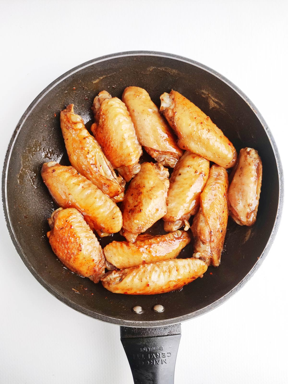 Fully cooked and glazed chicken wings in skillet.