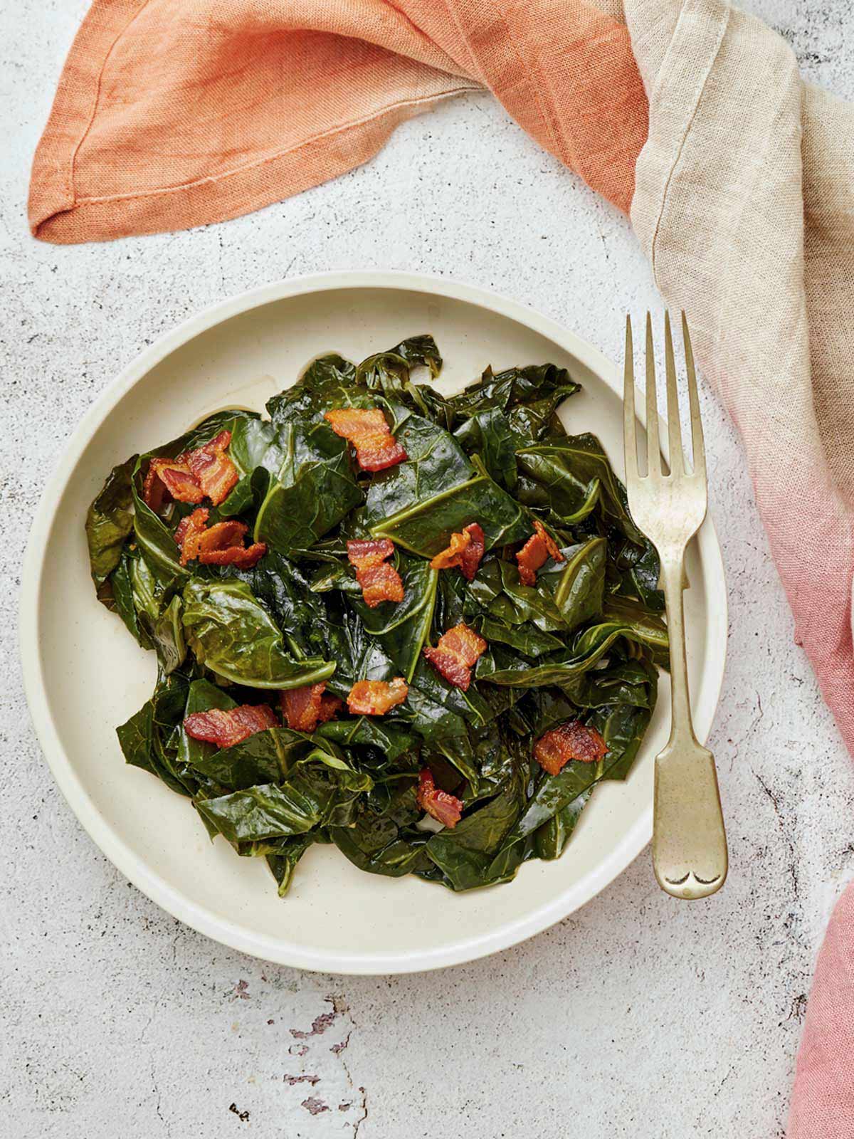 A plate of collard greens with bacon on the table.