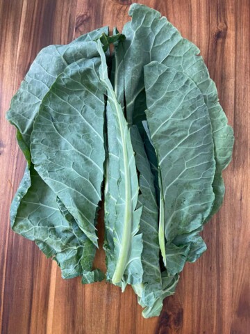 Collard greens stacked up with spines cut from the middles.