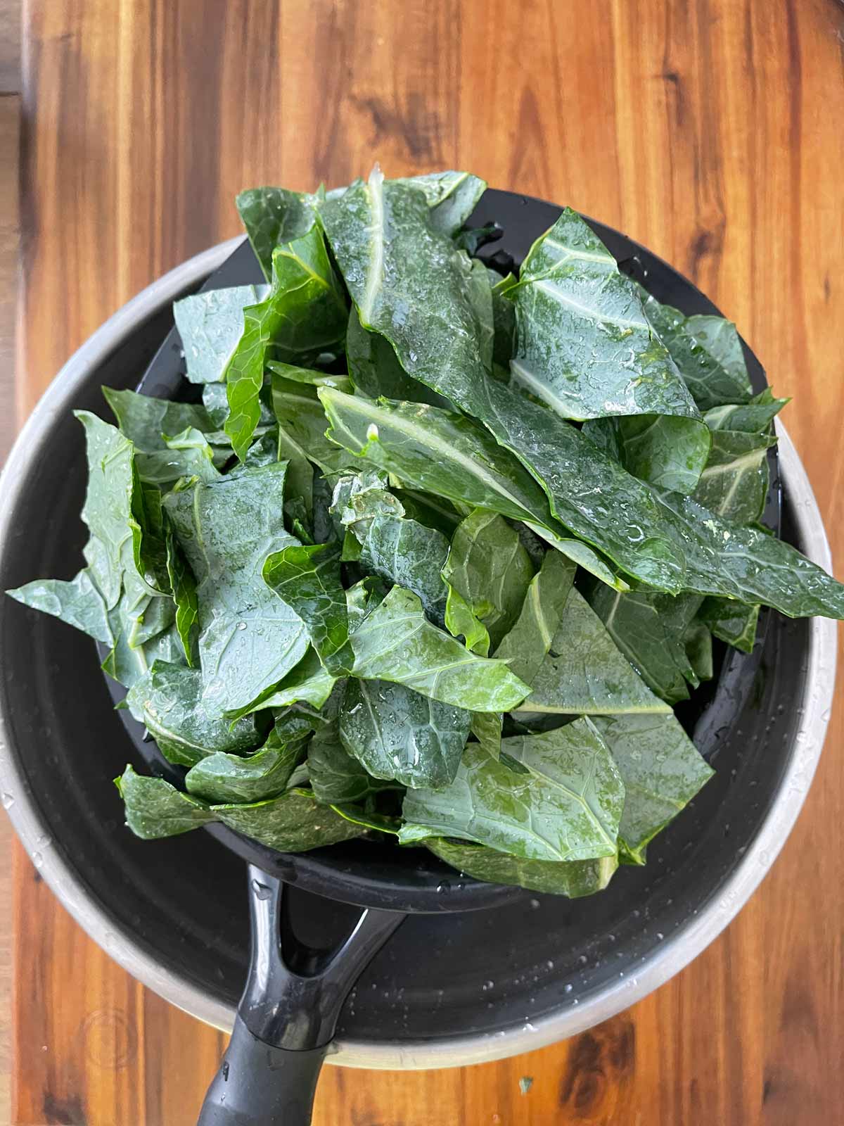 Chopped collard greens being washed in a sieve.