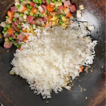 White rice added to wok with cooked vegetables.