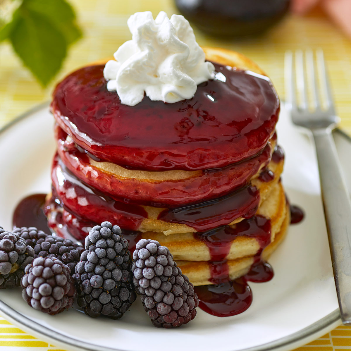Stack of pancakes with blackberry syrup dripping down.