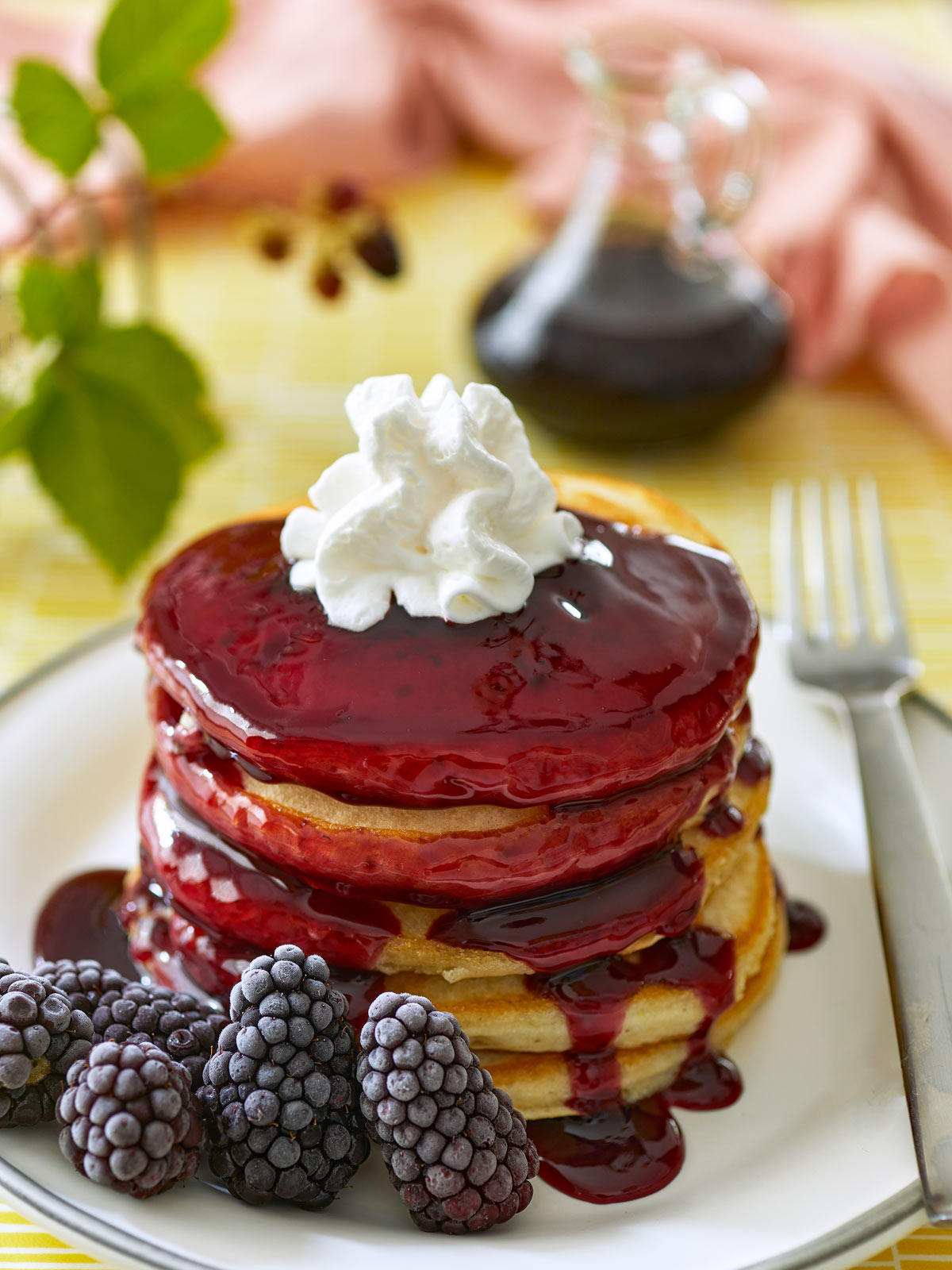 Blackberry syrup flowing over a stack of pancakes.