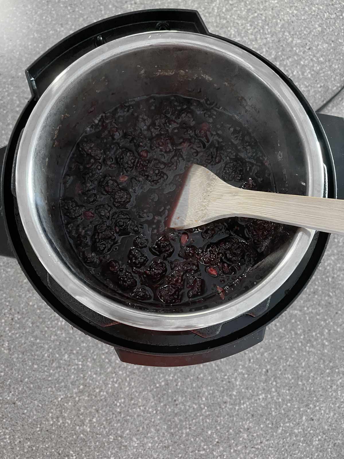 Wooden spoon being used to stir the blackberry/sugar mixture.