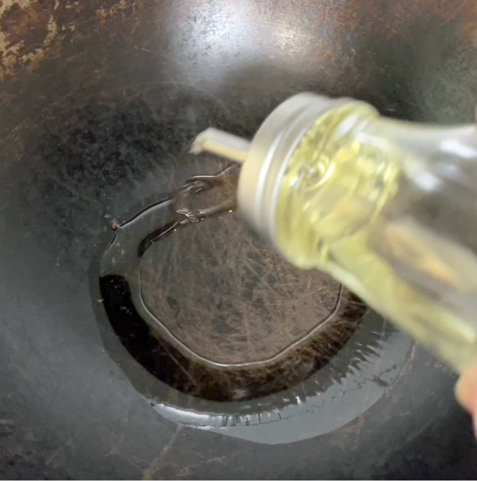 image showing oil being added to a wok.