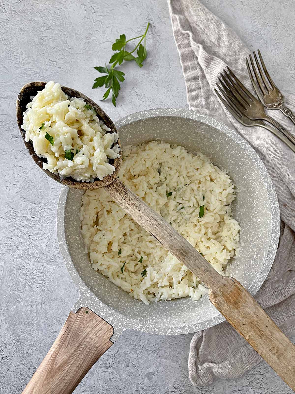 Bowl of cooked Creamy Parmesan Rice Recipe Copycat with a wooden spoon.