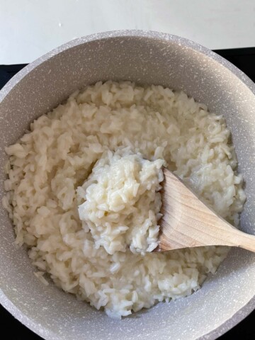 Cooked rice with wooden spoon.