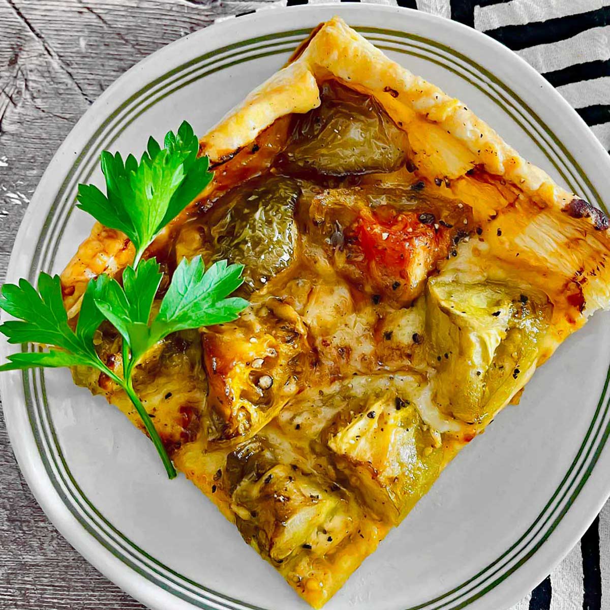 Square slice of tart with green tomatoes and cheese.