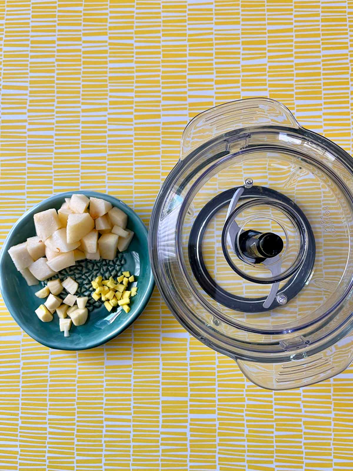 Image of mini food processor alongside chopped garlic, ginger, and pear.