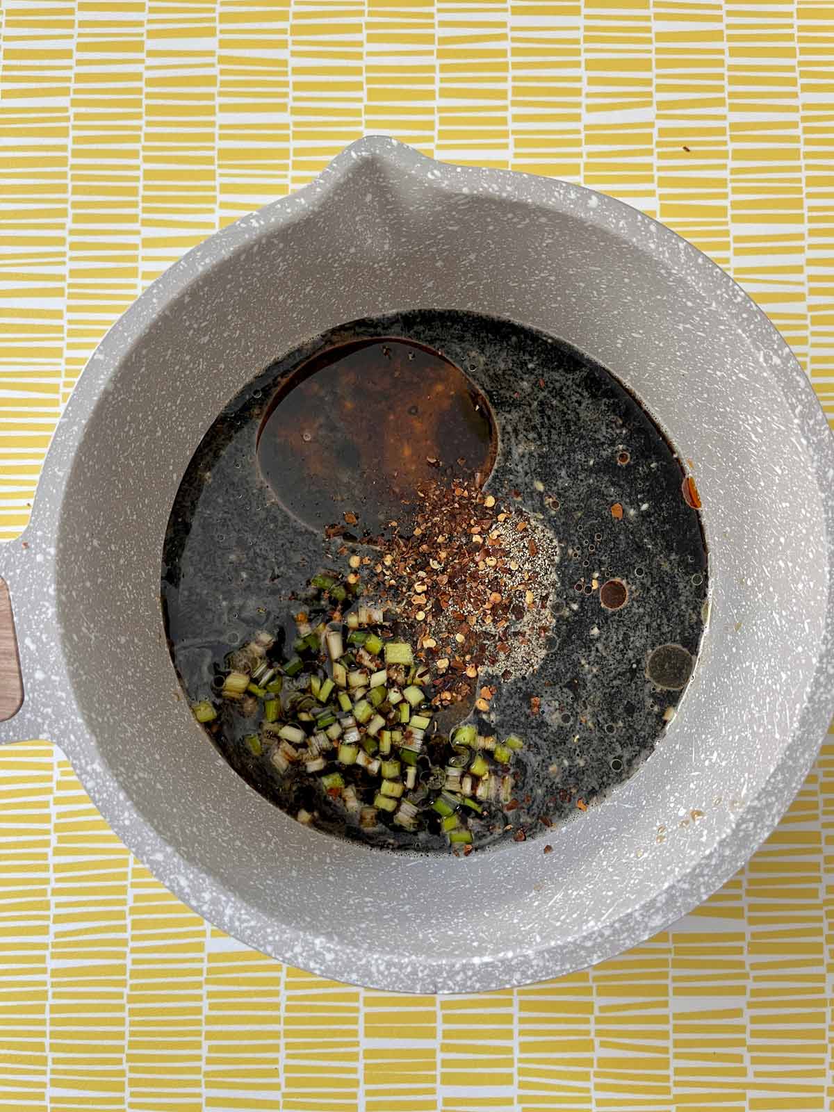 Soy sauce, and oils added to the saucepan with the pepper and green onion.