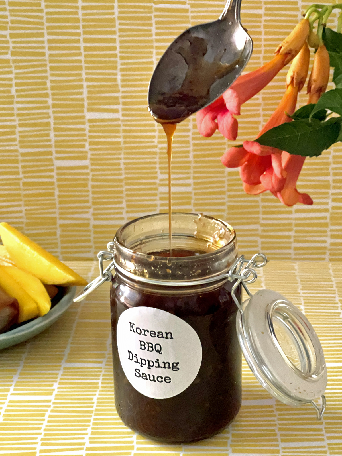 Bottle of Korean BBQ Dipping Sauce with sauce dripping from a spoon back into the jar.