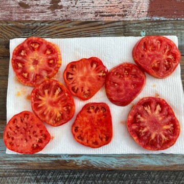 Sliced tomatoes on paper towels to drain juice from tomatoes.