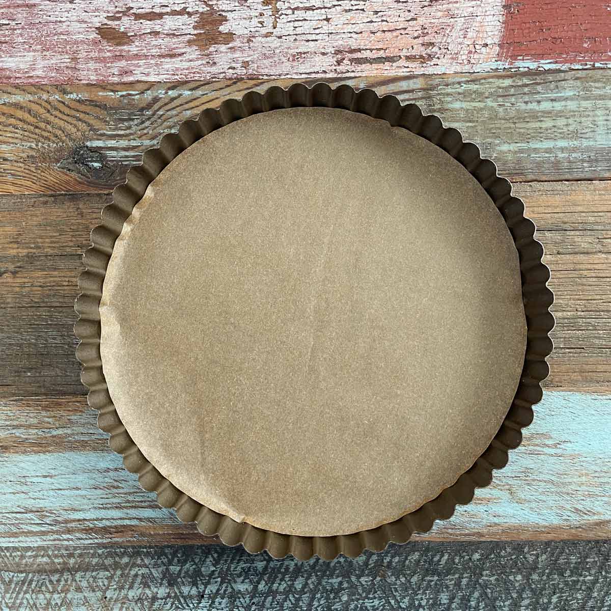 Tart pan with parchment paper lining.